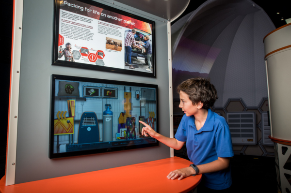 Child choosing what to pack for Mars on a screen.