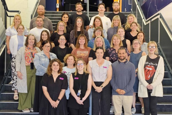 A group of newly graduated teachers smile at the camera